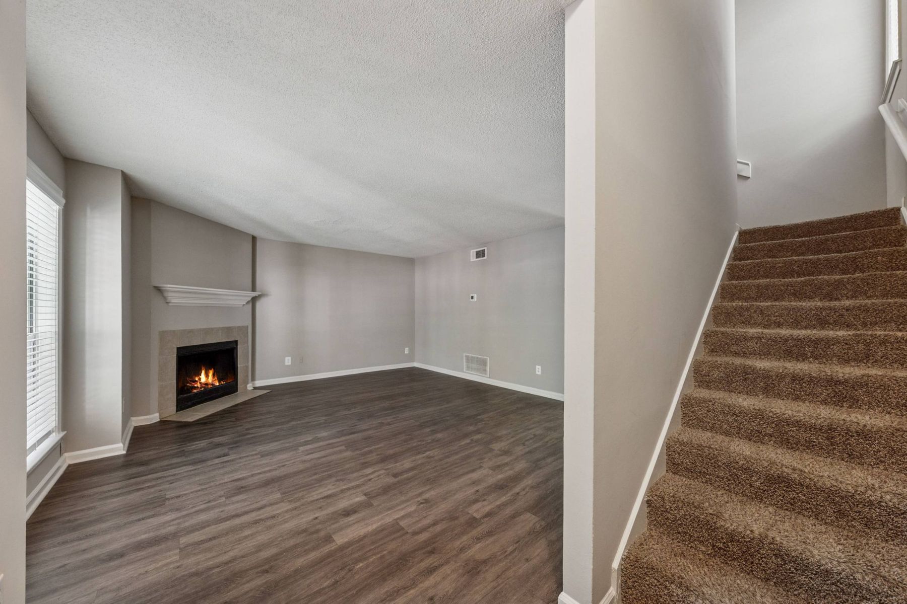 Empty room with wood floors, ceiling fan, and sliding glass door leading to a patio with vertical blinds at Apex West Midown.